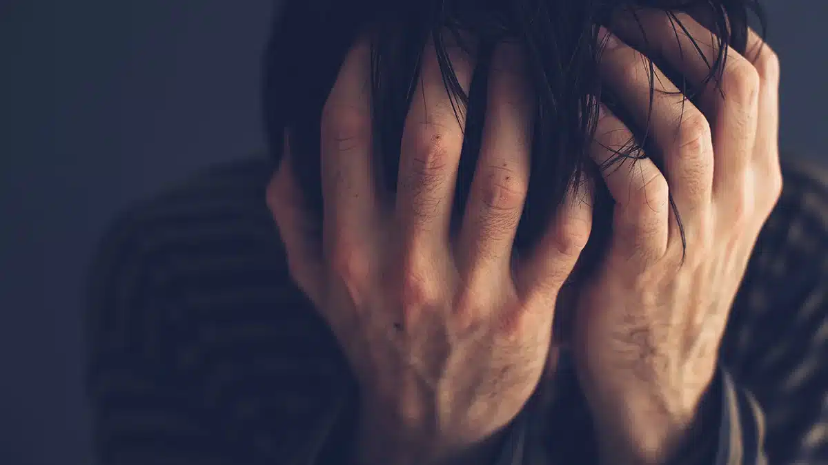 A close-up of a distressed person with their face buried in their hands, conveying a sense of emotional struggle or despair