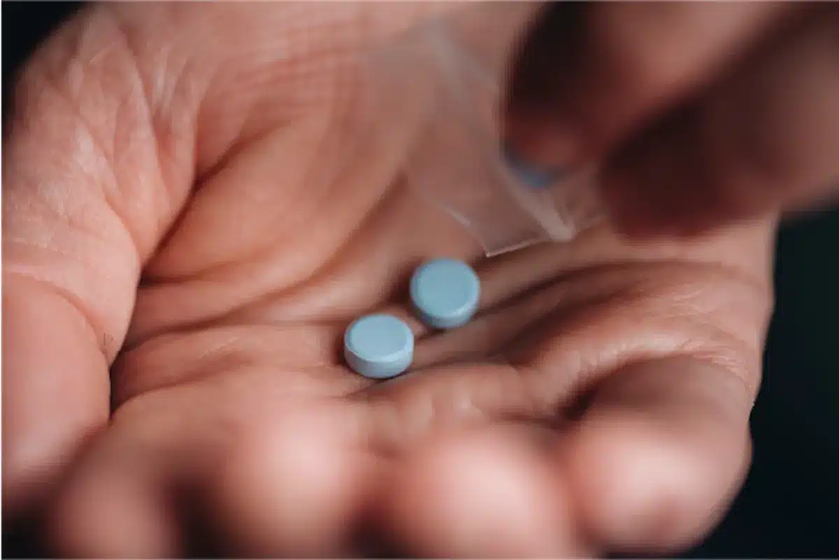 Close-up of a hand holding two blue pills