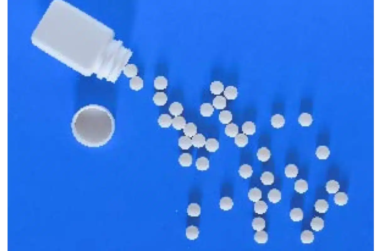 White pills spilling from a bottle on a blue background