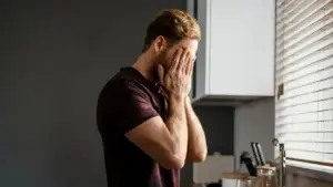 Man in distress with both hands covering his face