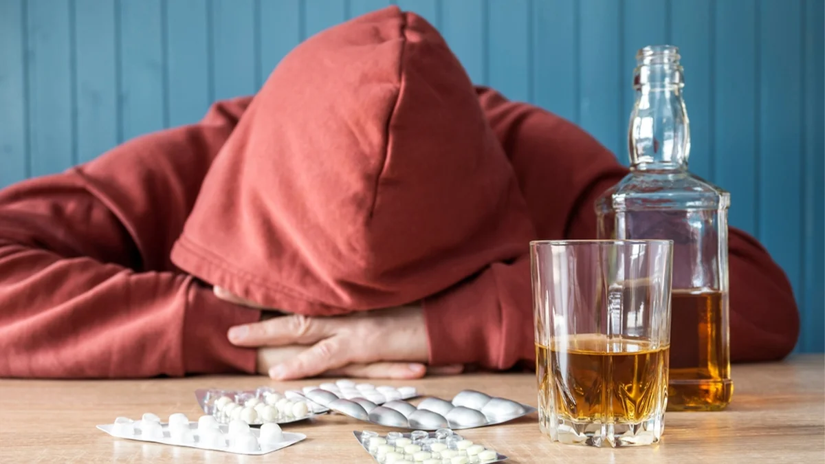 Man in a hoodie with his head in his hands. Alcohol can exacerbate mental health symptoms when used alongside antidepressants