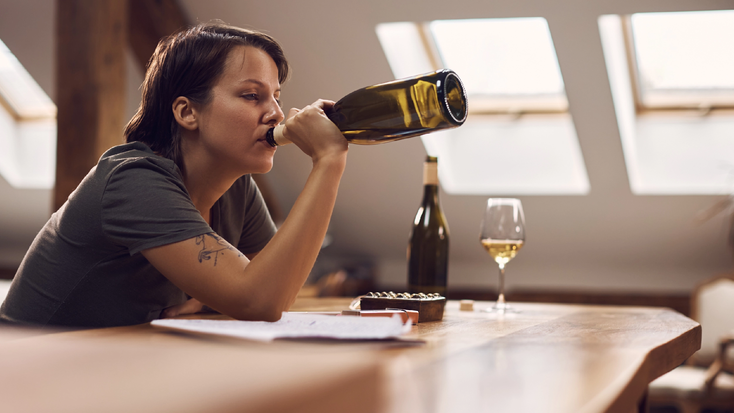 Person drinking wine straight from the bottle. Graphic lists long-term dangers of binge drinking, including heart problems and liver damage.