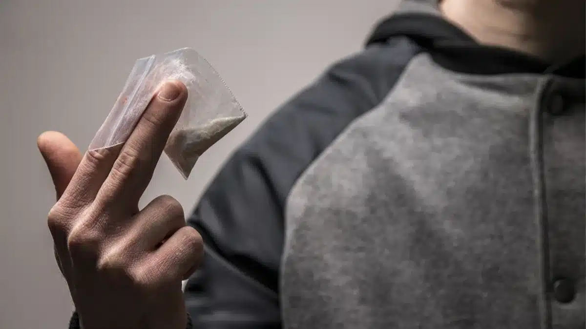Man holding a small bag of cocaine.