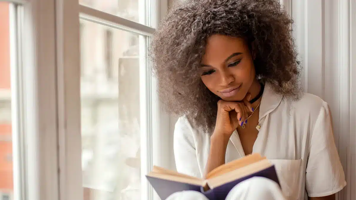 A person with curly hair reading a book