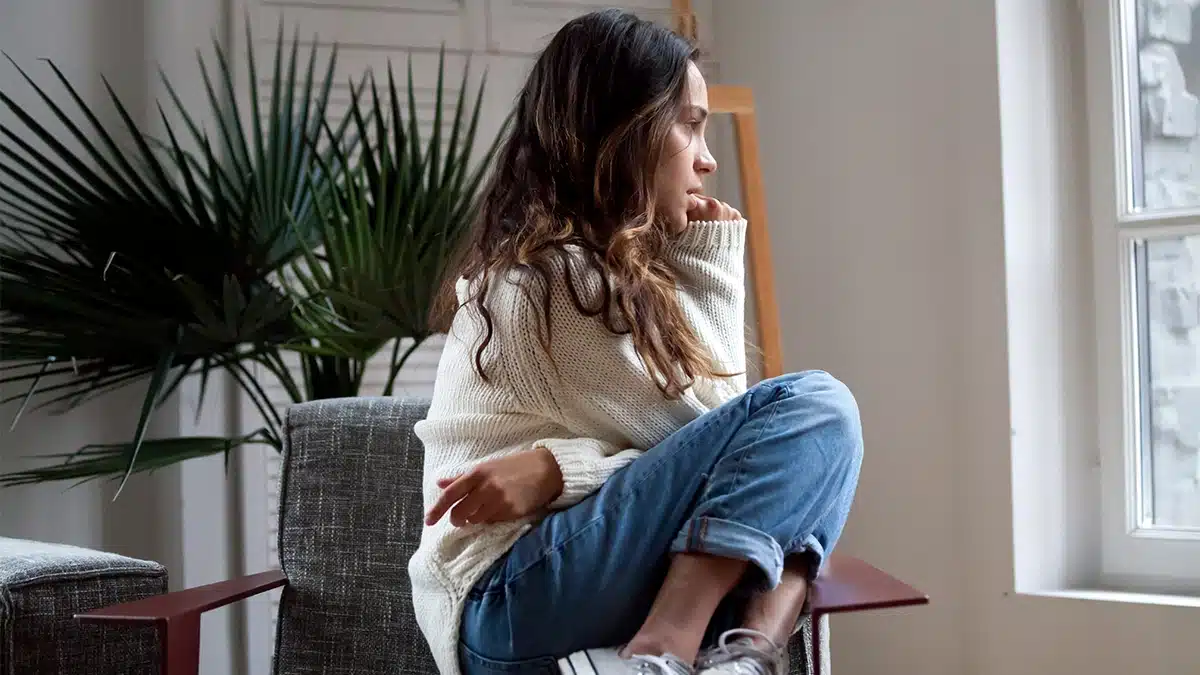 distressed woman sitting down while looking towards a window