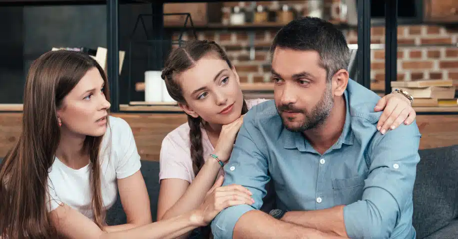 Image of two daughters comforting their father.