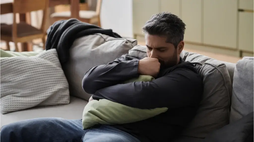 Anguished man holding a pillow tightly to his chest