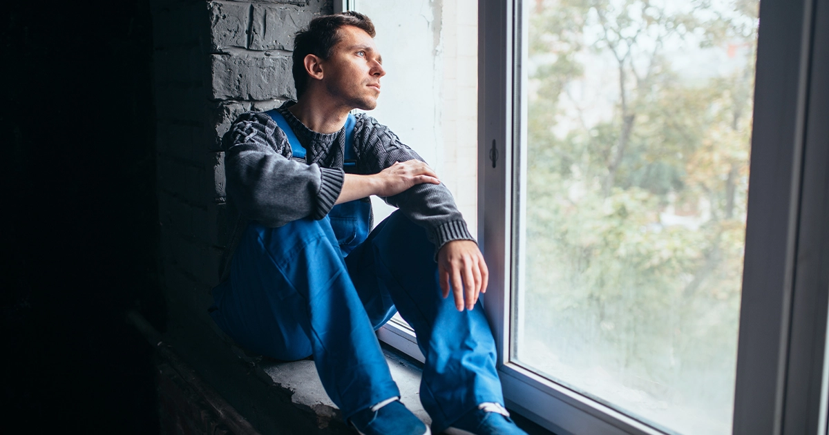 saddened man looking out of a window