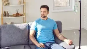 Man sitting on a couch with IV in his arms