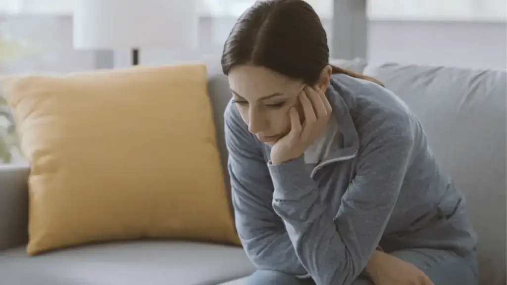 woman solemnly looking down while she rests her chin on her hand