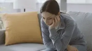 woman solemnly looking down while she rests her chin on her hand