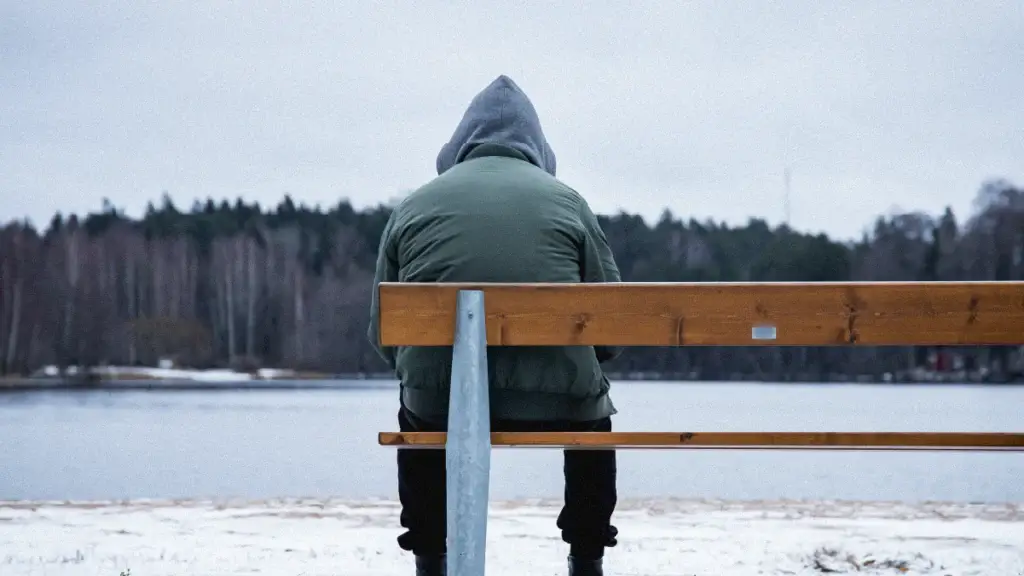 man sitting at the end of a bench in the winter