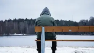 man sitting at the end of a bench in the winter
