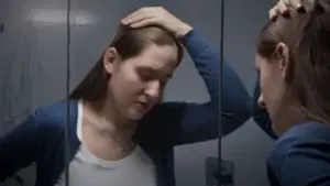 saddened woman looking at herself in a mirror