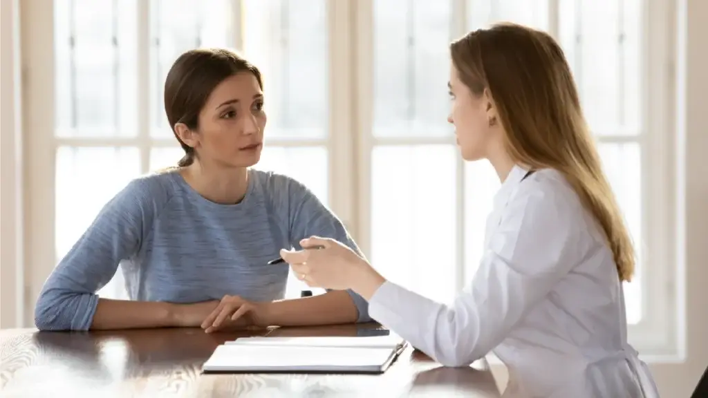 Doctor talking to her patient as the patient listens with concern