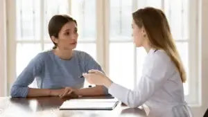 Doctor talking to her patient as the patient listens with concern