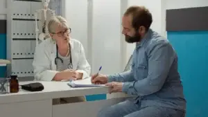 doctor talking to patient as the patient is writing