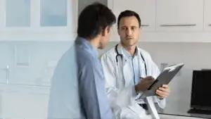 A doctor talking to a patient with a clipboard in his hand