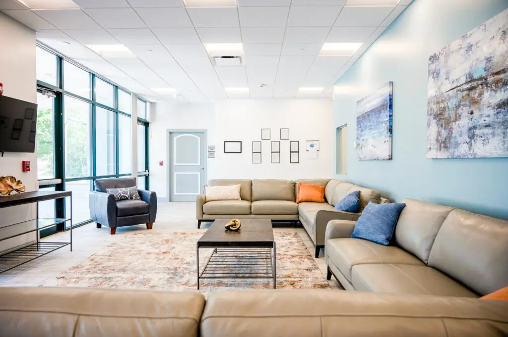 Modern rehab facility lounge with comfortable leather seating, bright natural lighting, and welcoming environment for addiction treatment and recovery support.