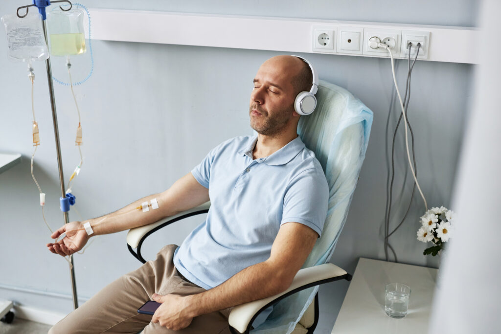 A patient sitting down with headphones on receiving IV treatment