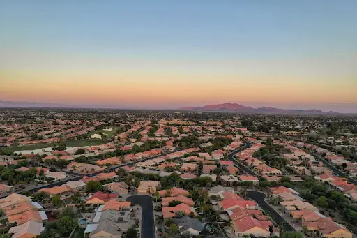Vista aérea de un barrio suburbano de Arizona al atardecer con las montañas a lo lejos.