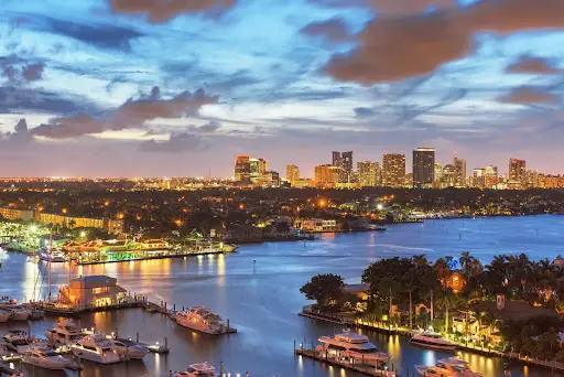 Evening aerial of Fort Lauderdale waterfront with boats and skyline at sunset.