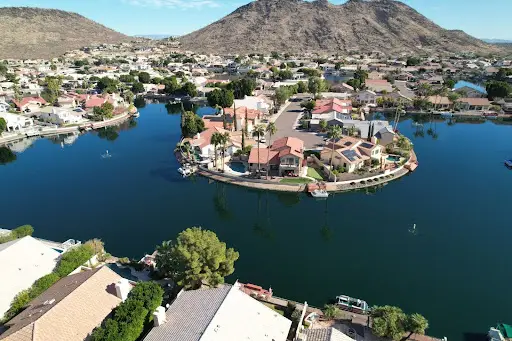 Arizona - vista aérea de comunidad con casas y lago rodeada de montañas desérticas.