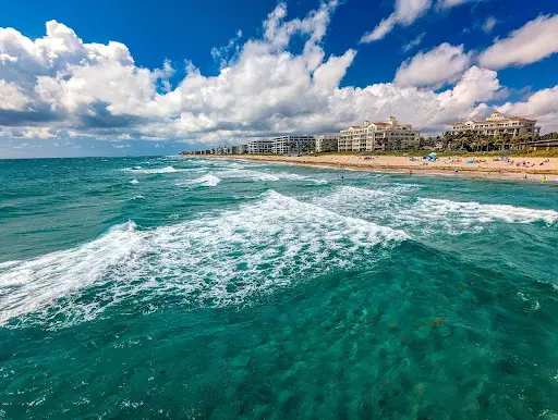 Ocean wave cresting near the shoreline under blue sky.