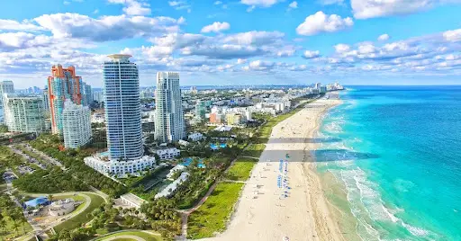 Aerial view of Miami Beach with tall oceanfront buildings and sandy shoreline.