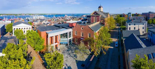 Aerial view of New Bedford, Massachusetts with red-brick buildings and harbor in background.