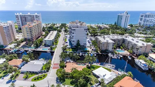 Vista aérea de las calles de una ciudad con edificios de mediana altura y el océano al fondo.