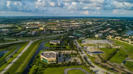 Vista aérea de los edificios y carreteras de Pot St Lucie bajo un cielo parcialmente nublado.