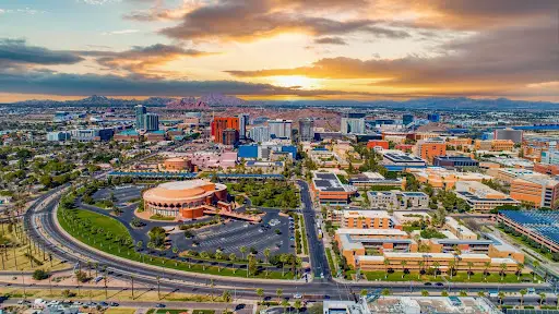 Tempe, Arizona — aerial cityscape at sunset with stadium, buildings, and mountain backdrop.