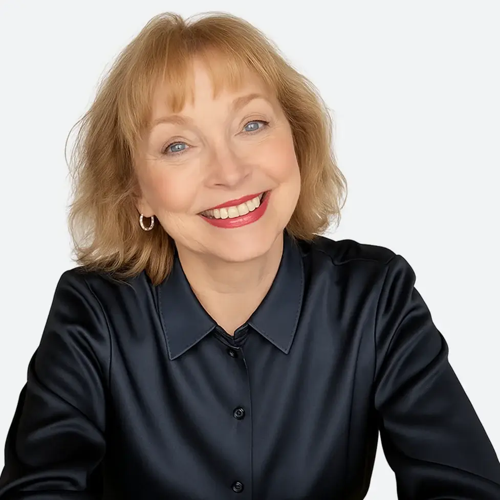 Professional headshot of a smiling woman with short blonde hair, wearing a dark blouse against a white background.