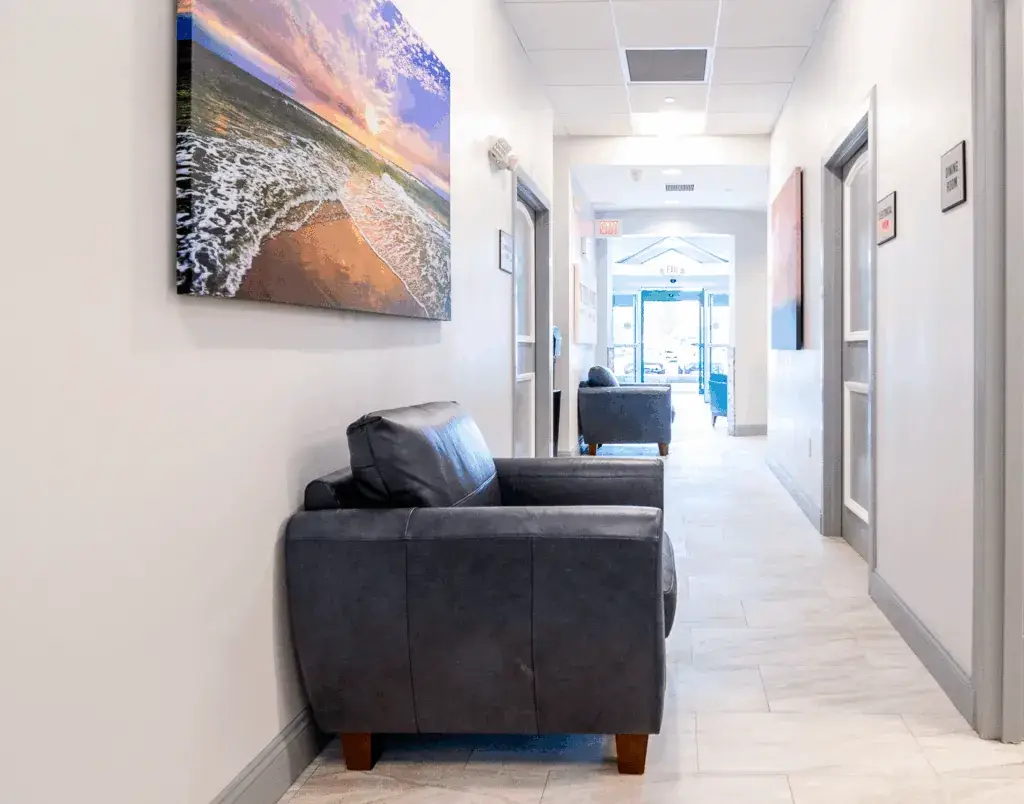 Modern addiction treatment facility hallway with comfortable seating and calming coastal artwork